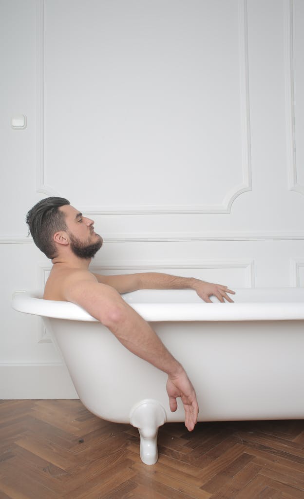A man relaxing in a bathtub in a minimalist indoor setting, perfect for leisure concepts.