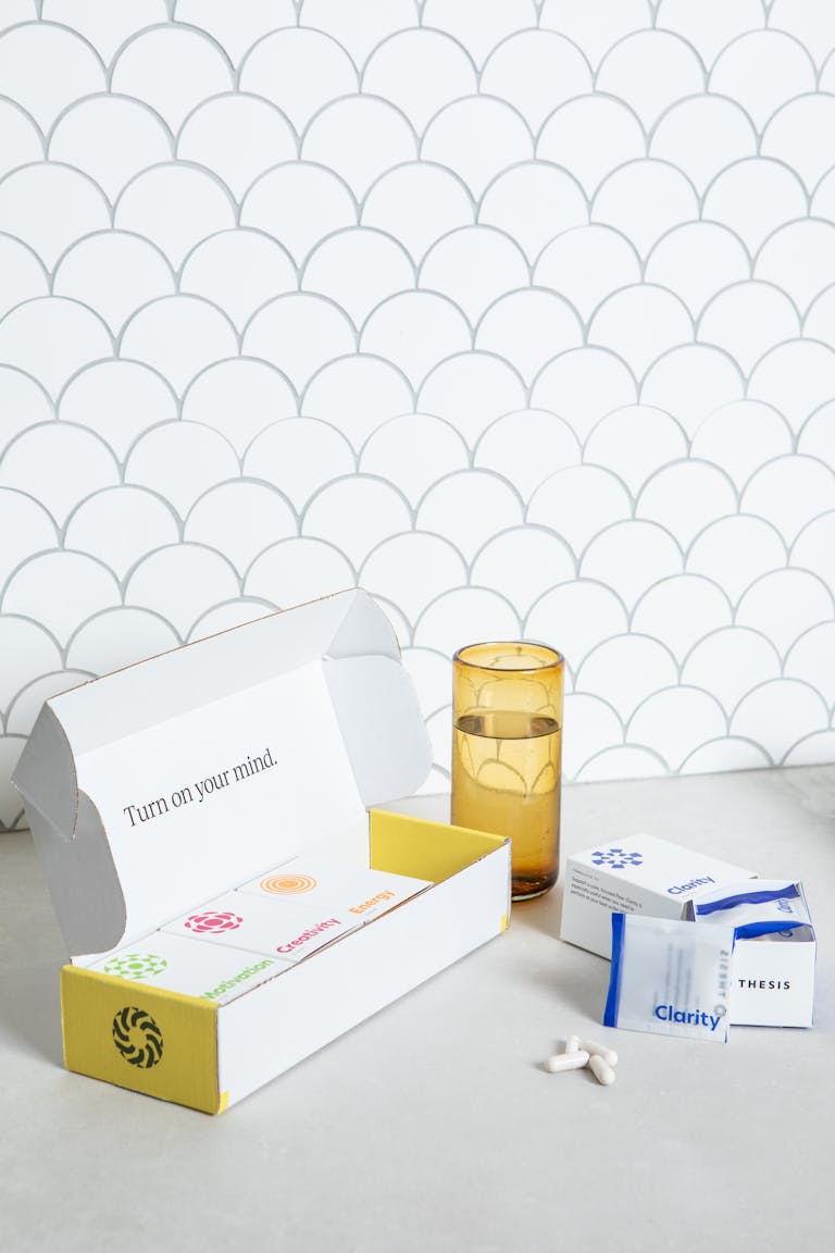 Box of nootropic supplements with pills and glass on a white background.