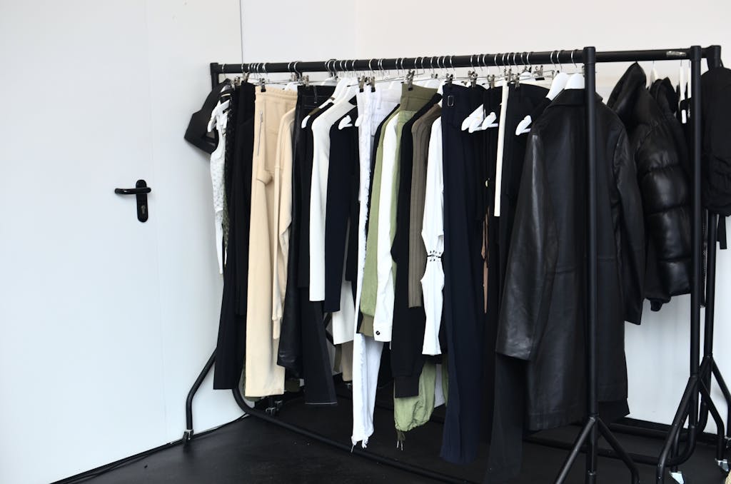 Stylish wardrobe with diverse clothing collection on a black rack in a bright room.