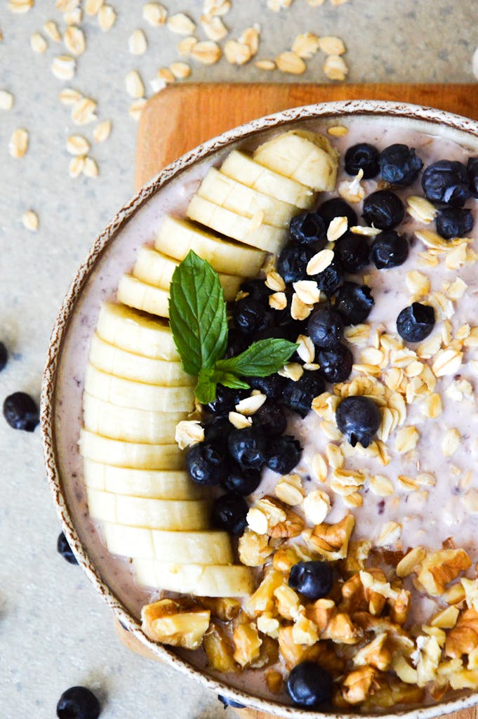 Top view of a breakfast bowl with bananas, blueberries, oats, and walnuts.